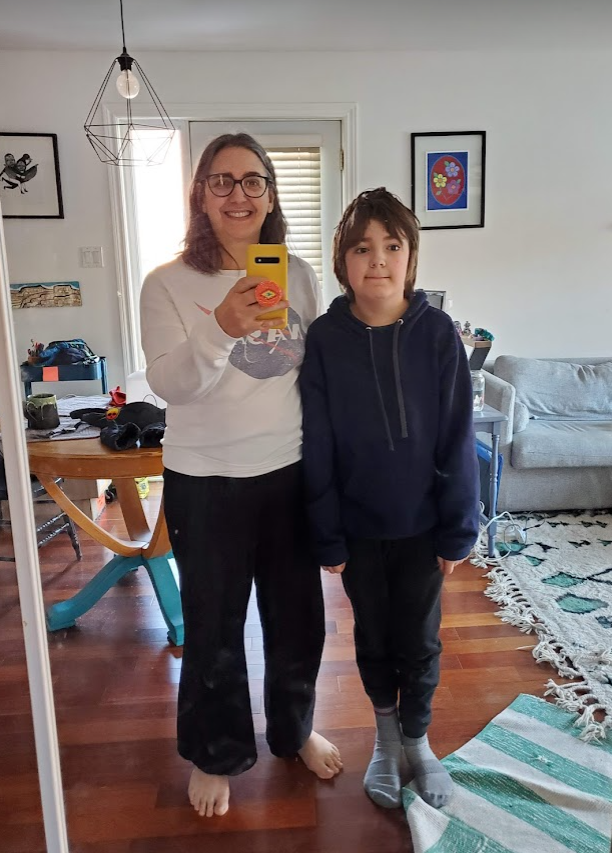 Mother and child in front of a mirror. The mother is holding phone in a yellow case in front of her, taking a selfie of the two of them.